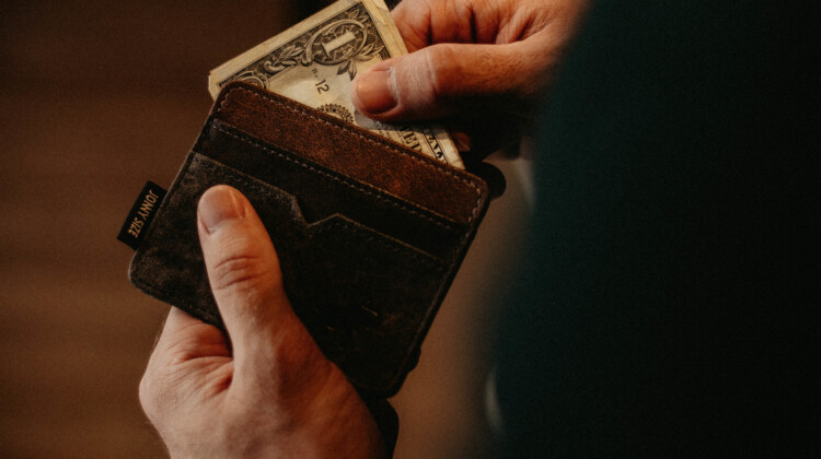a person holding a wallet with money