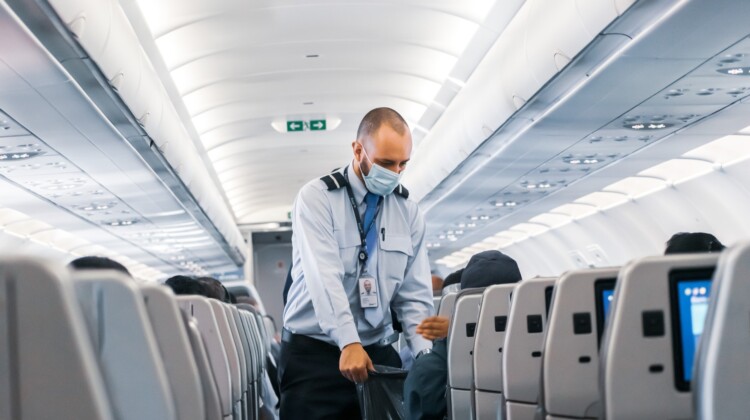 a man wearing a mask and holding a bag in an airplane