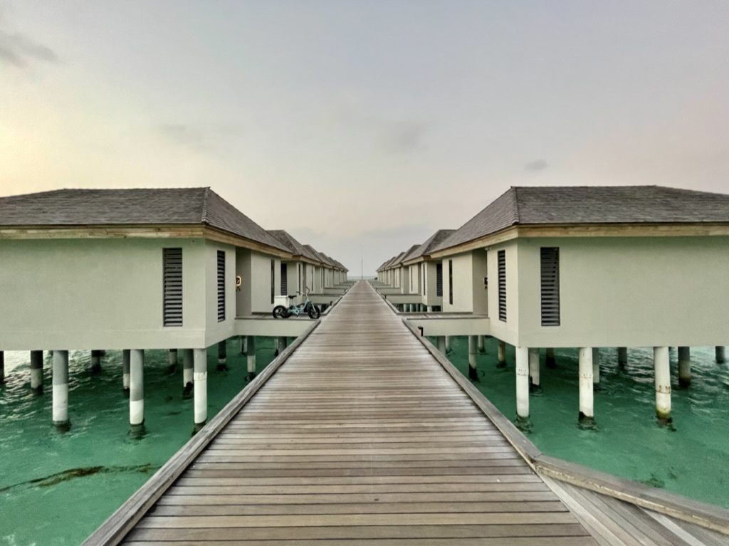 a long wooden walkway leading to a row of houses on stilts
