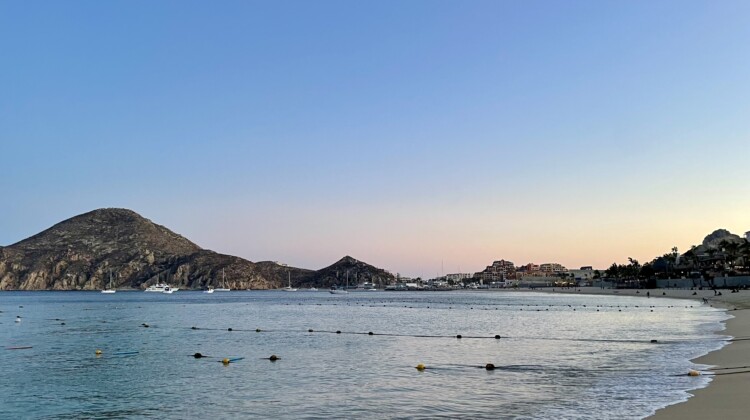 a beach with a body of water and a hill in the background