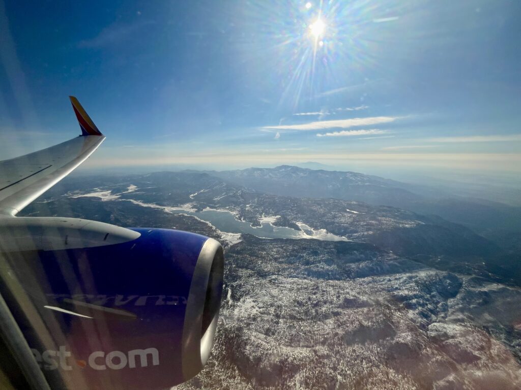 an airplane wing and engine of an airplane flying over a snowy mountain