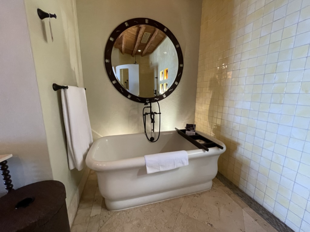 a bathroom with a round mirror and tub