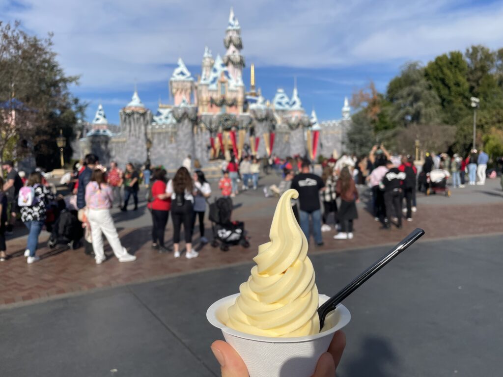 a hand holding a cup of frozen yogurt in front of a castle