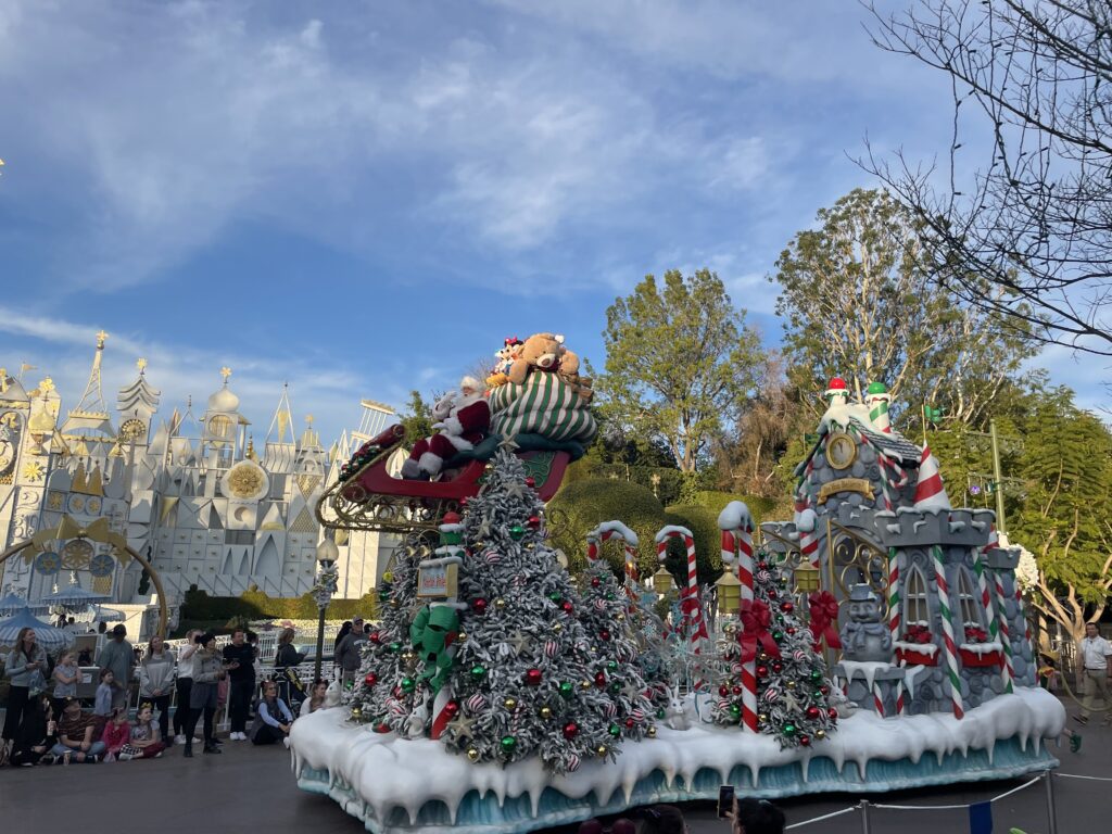 a float with a christmas tree and buildings in the background