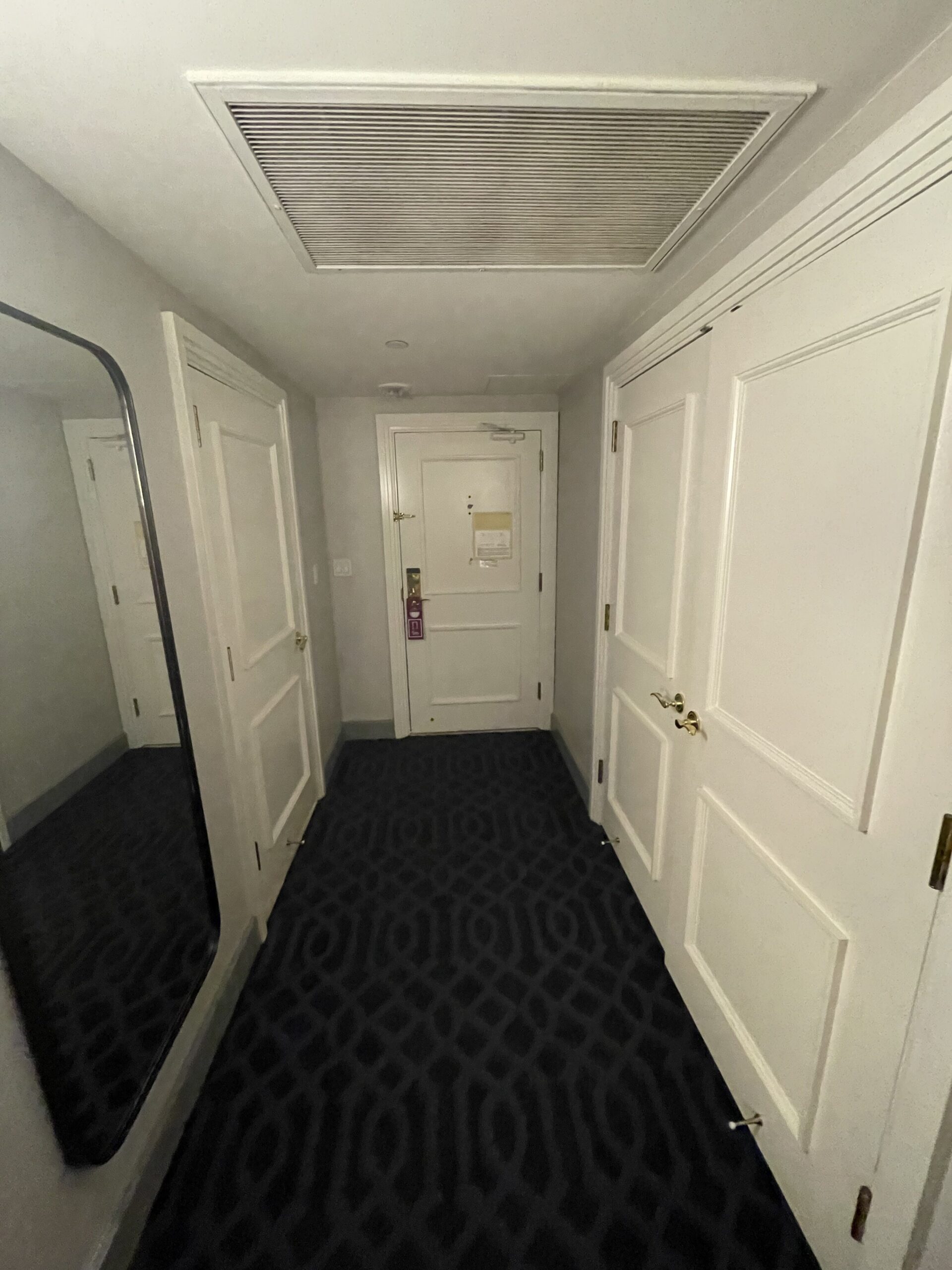 a hallway with white doors and a mirror