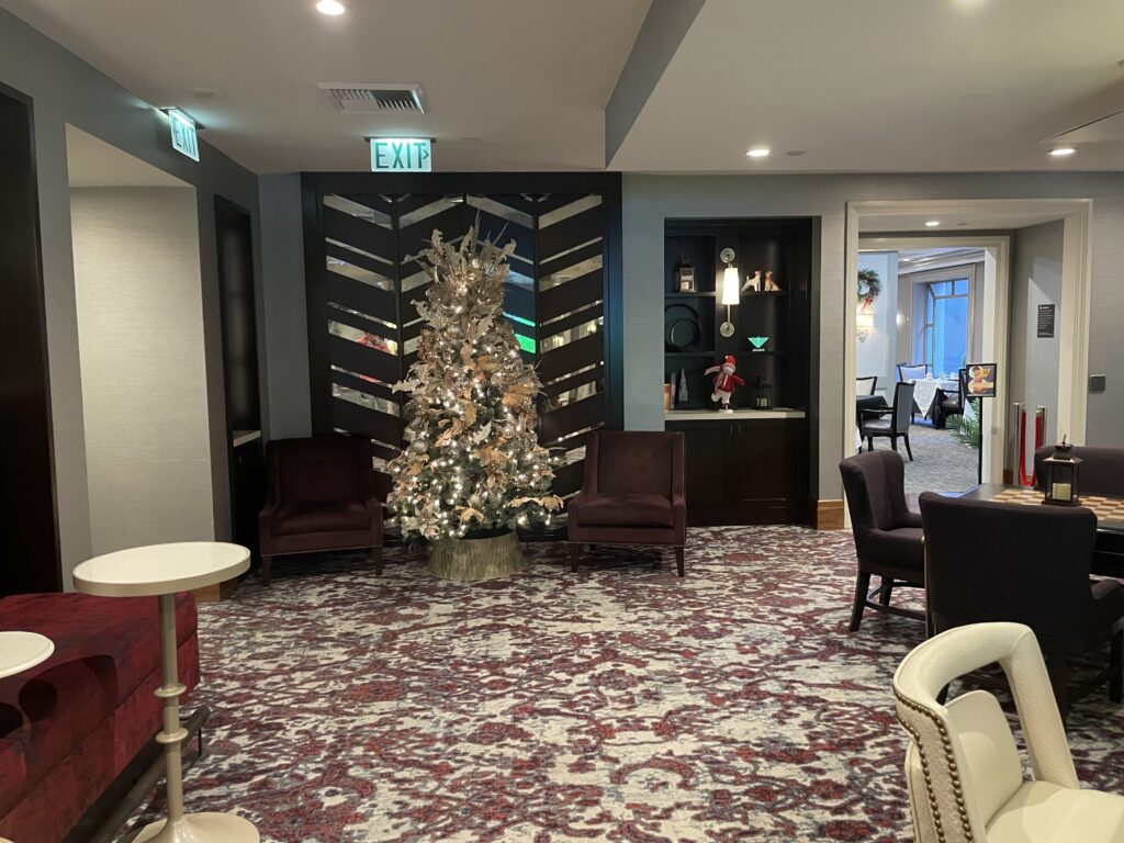 a room with a christmas tree and chairs