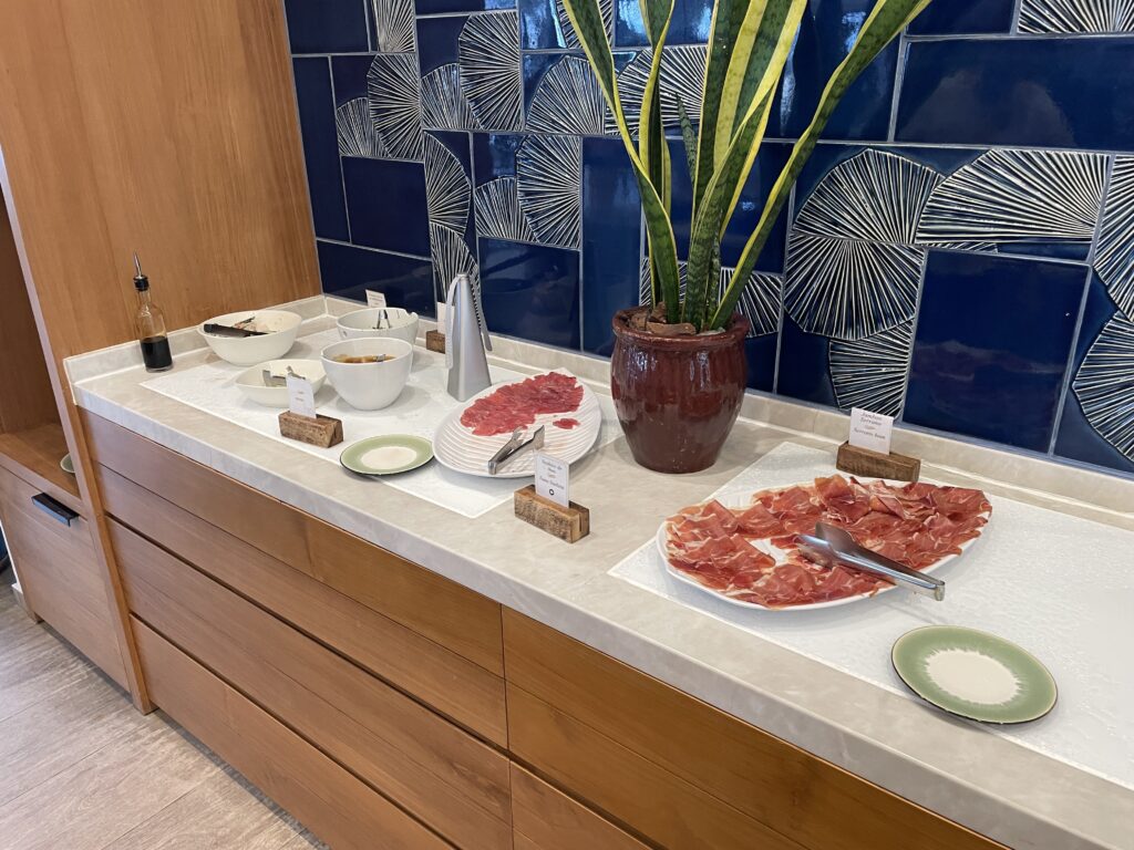 a buffet table with plates of meat and a plant