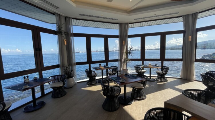 a room with tables and chairs and a view of the water