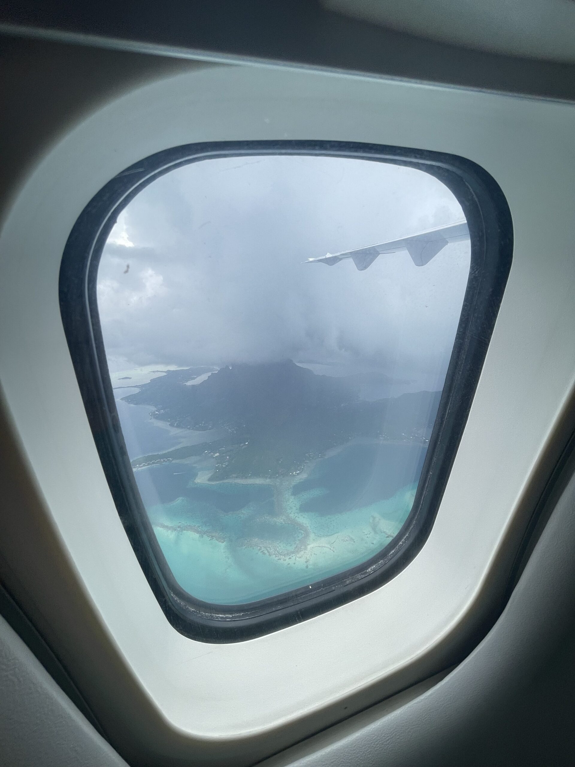 an airplane window with a view of the ocean and land