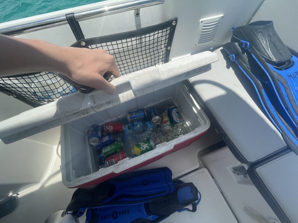 a cooler with drinks and other items on the deck of a boat