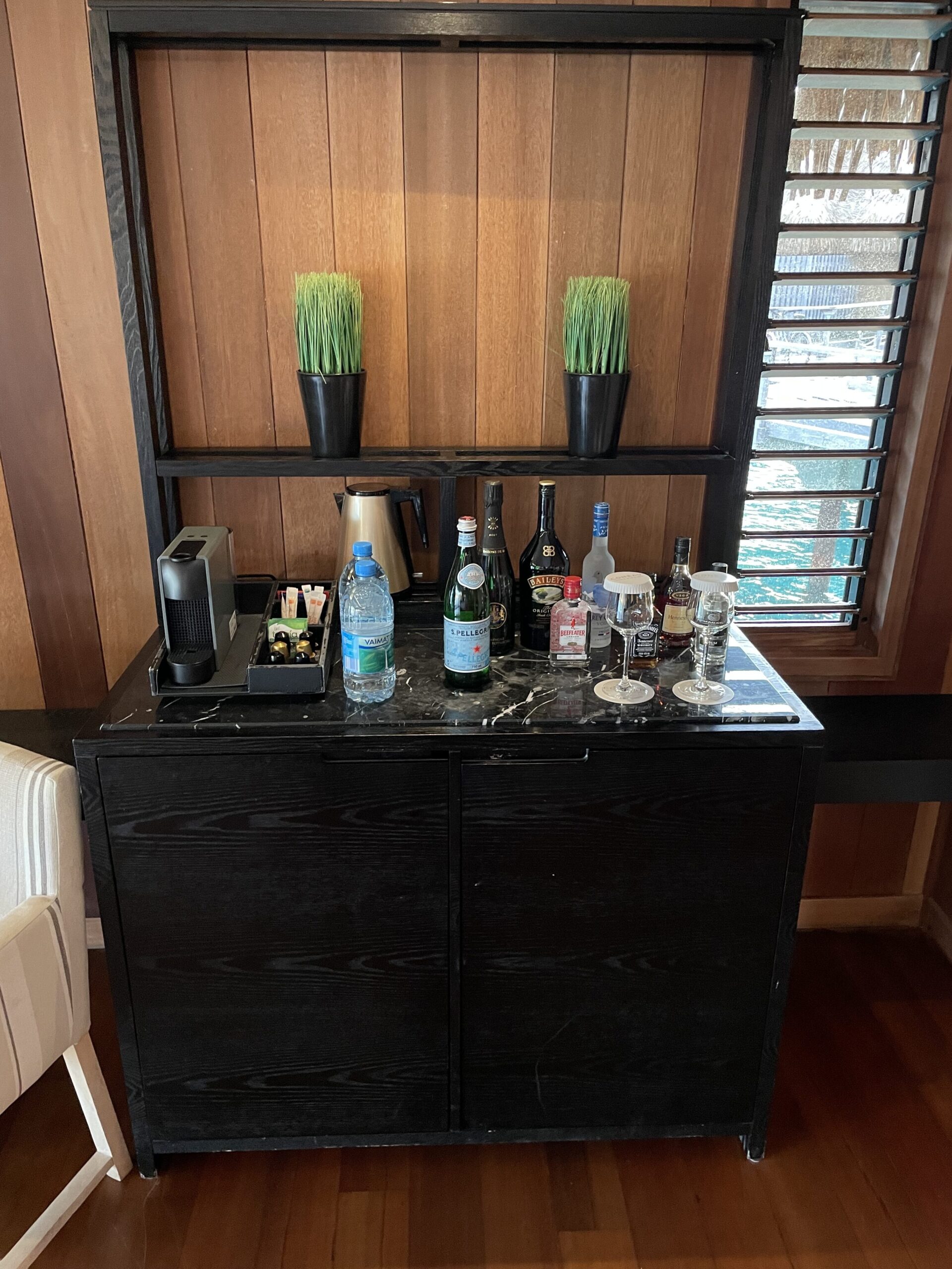 a black cabinet with bottles and glasses on top