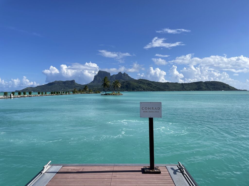 a dock with a sign on it and a body of water with mountains in the background
