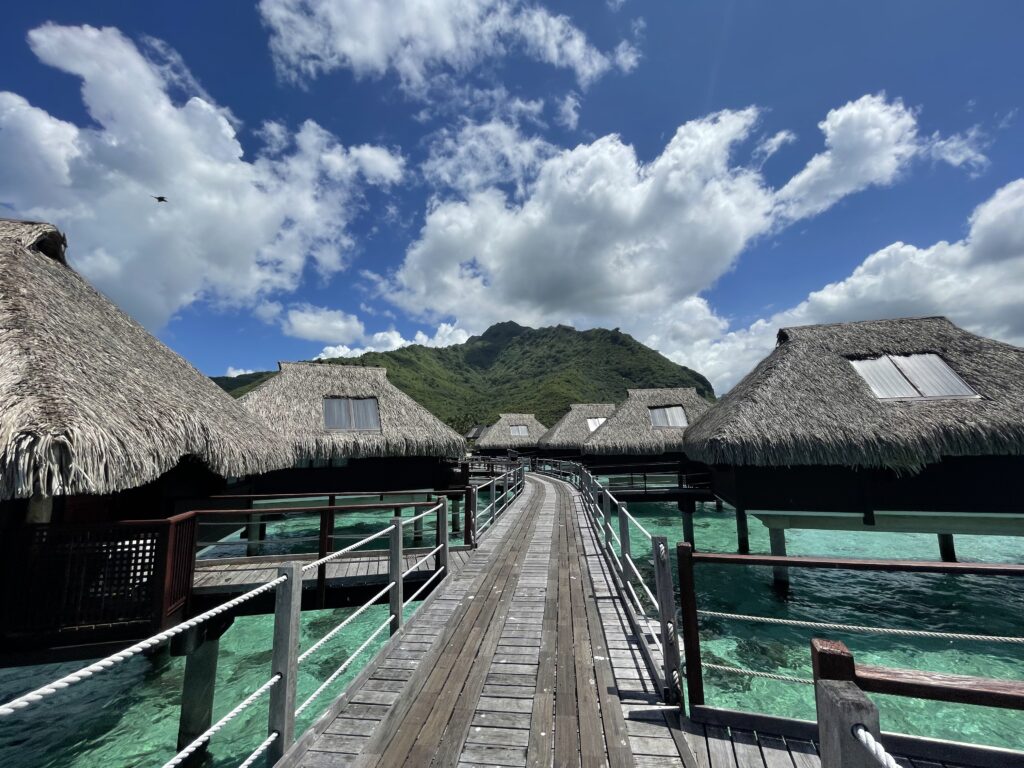 a wooden walkway leading to a hut over water