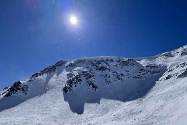 a snow covered mountain with blue sky and sun