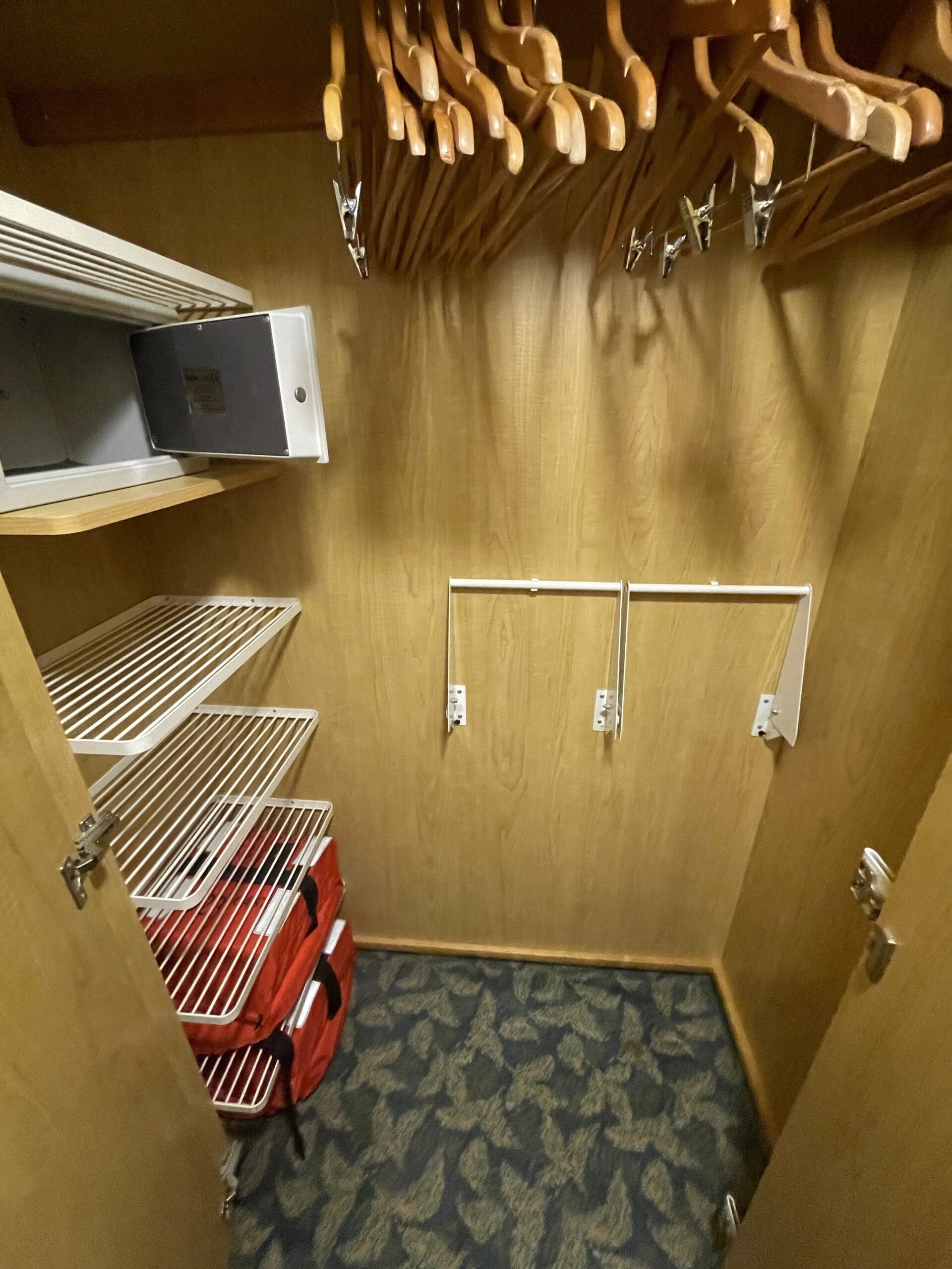 a closet with a door open and a shelf with a red bag