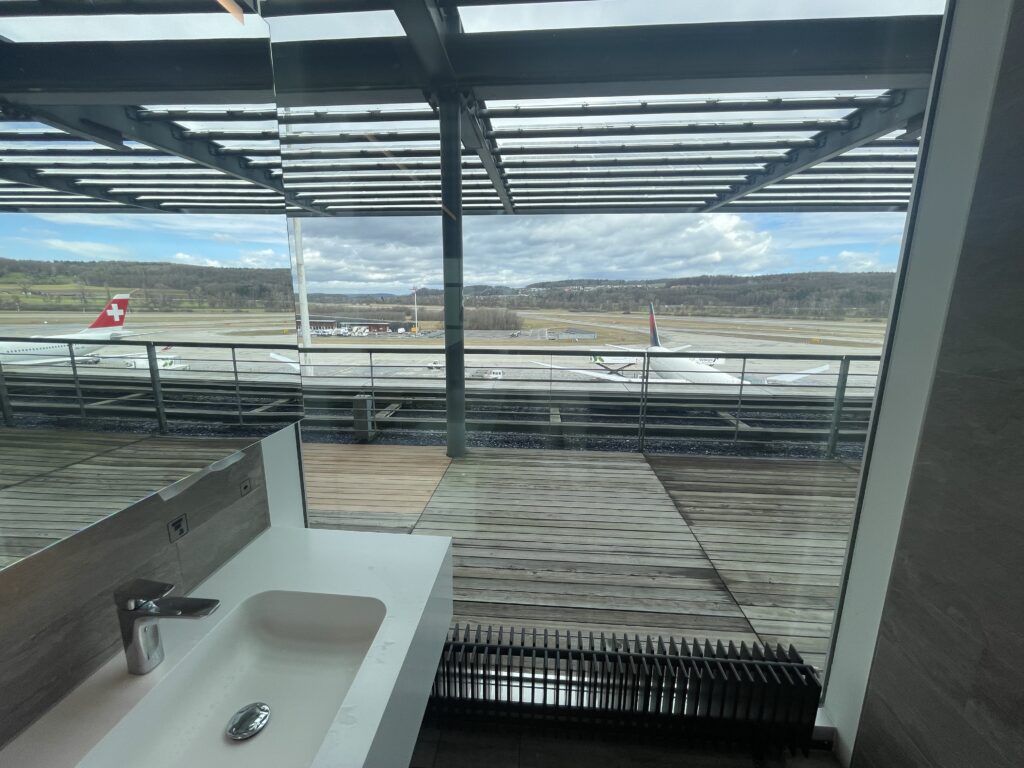 a bathroom with a window and a sink and a plane in the background