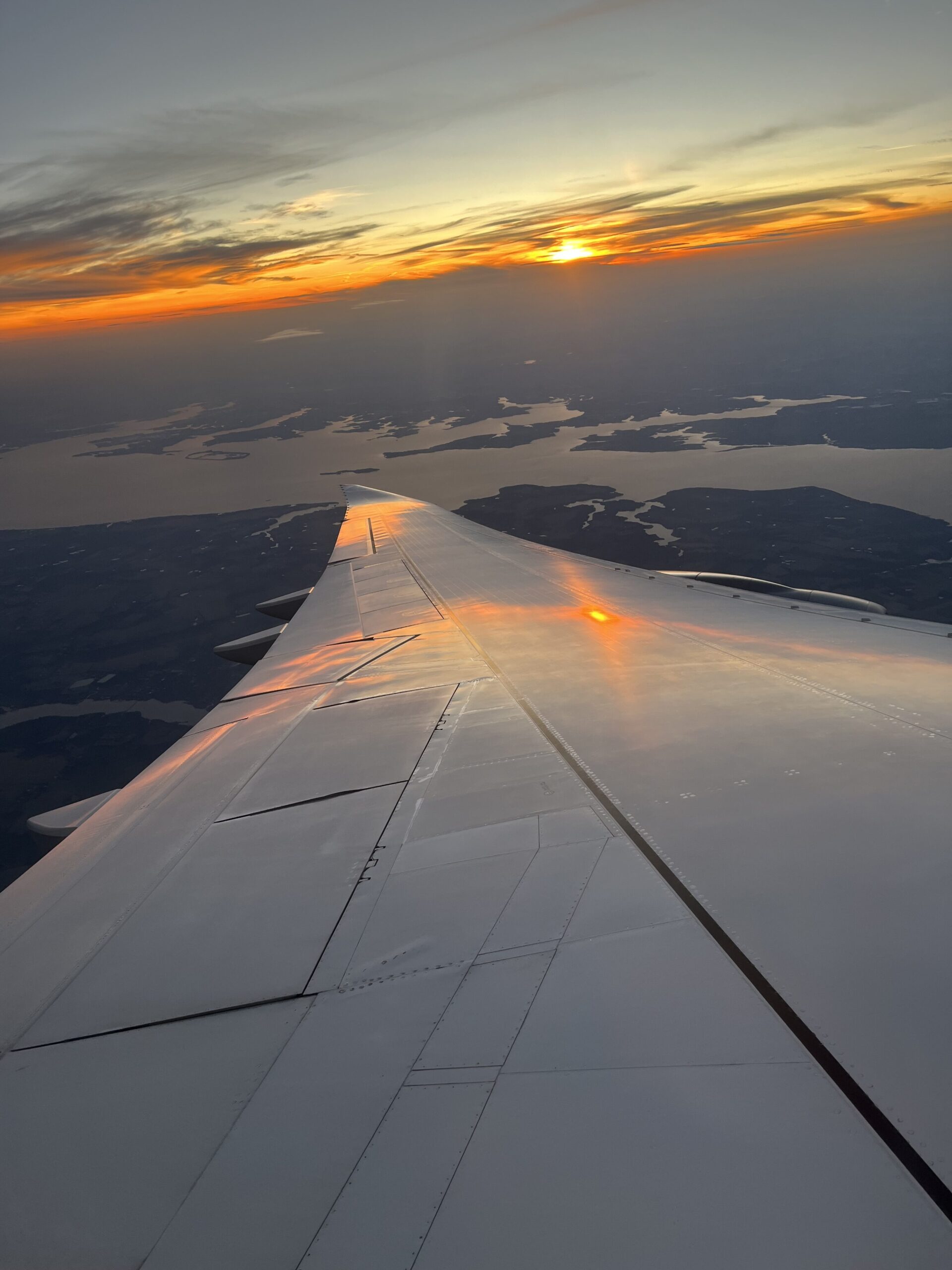an airplane wing with the sun setting over the horizon