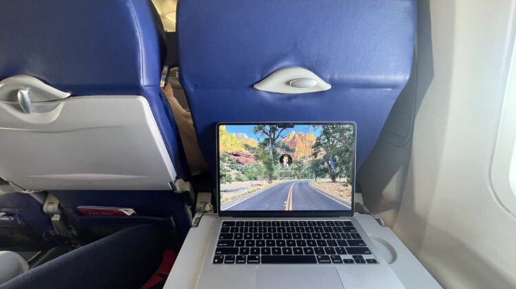 a laptop on a table with a screen on the side of the seat