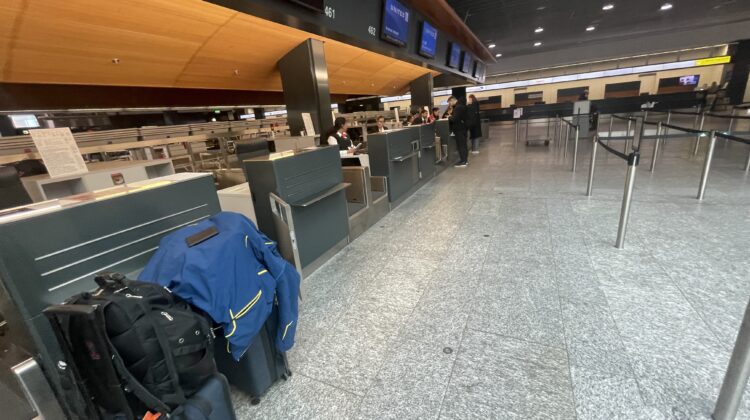 luggage in a terminal with people standing in front of it