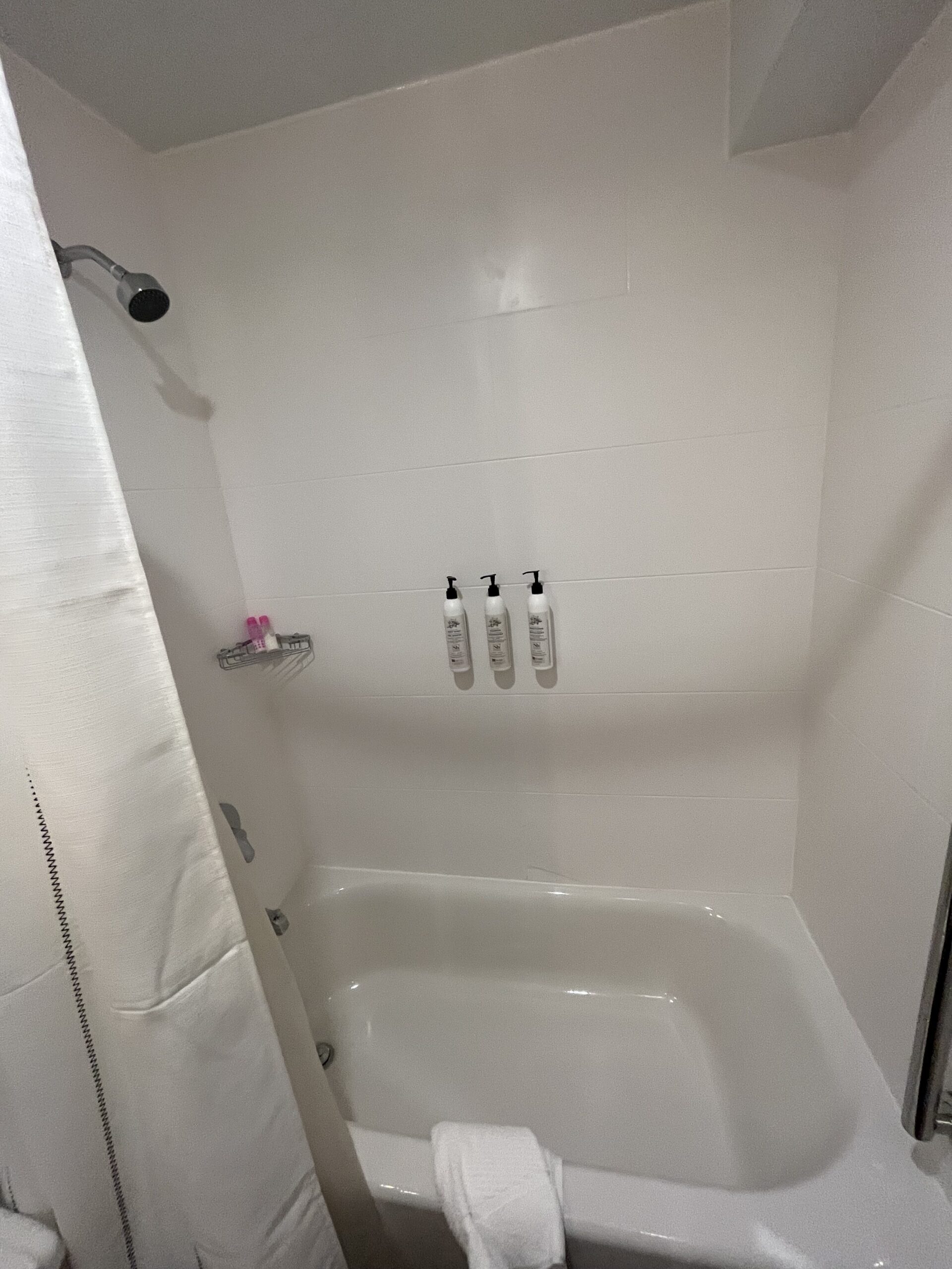 a shower with white walls and white shower curtain