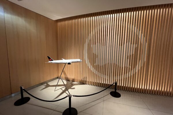 a model airplane on a stand in a room with a rope and a logo on the wall