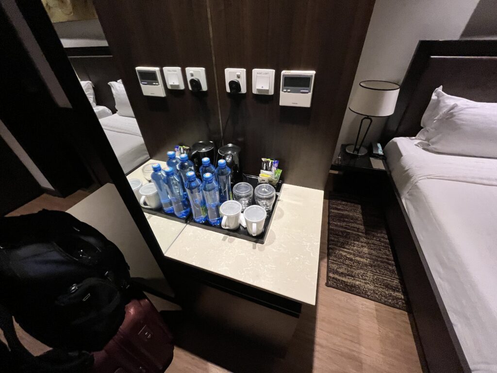 a hotel room with a mirror and a tray of water bottles