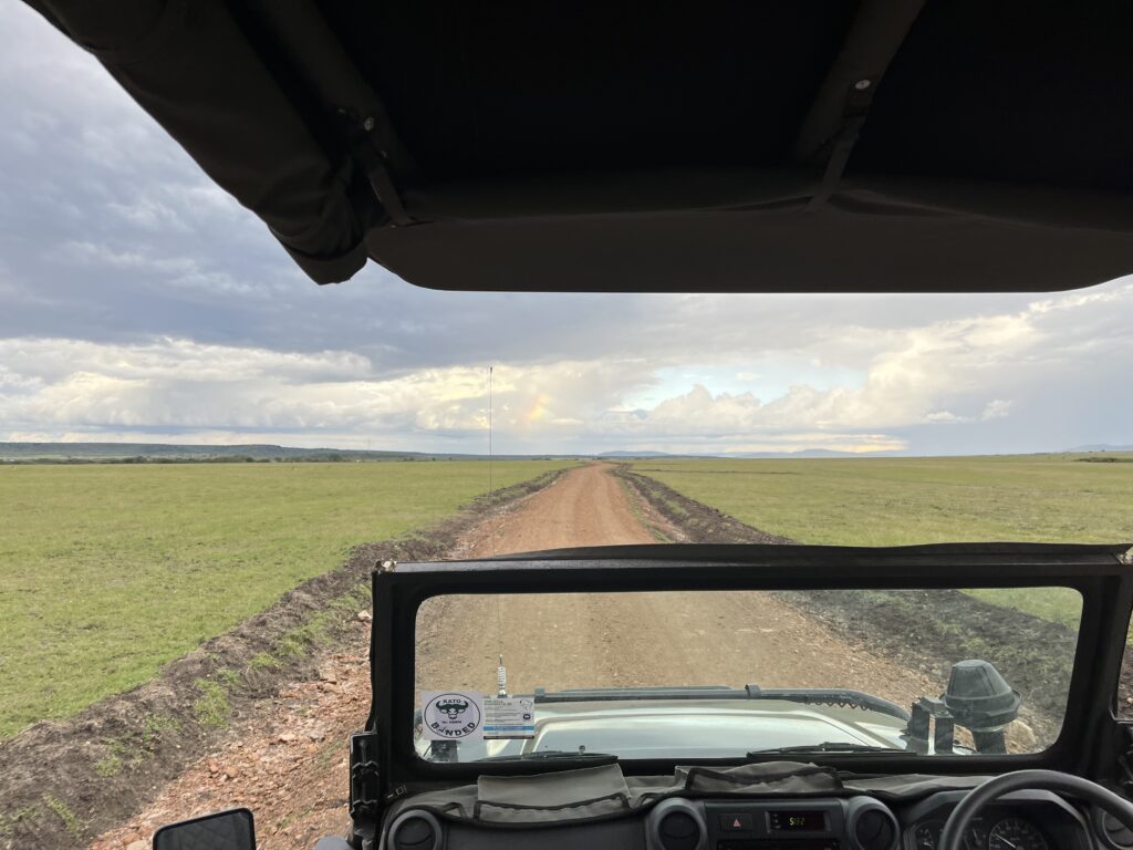 a view from a jeep on a dirt road through a field